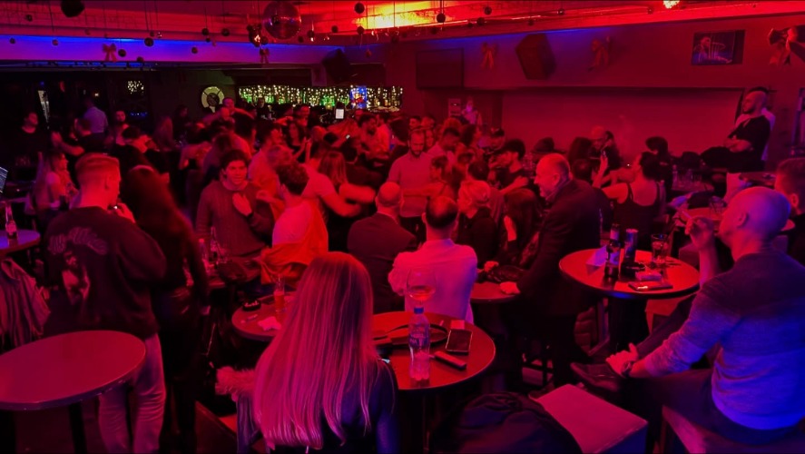Packed dance floor under red lights at The Velvet Bar